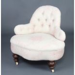 A Victorian shaped nursing chair upholstered in pink floral patterned material, raised on turned