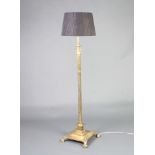 A gilt metal reeded column standard lamp with Corinthian capital raised on a square base with paw