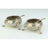 A pair of Victorian circular embossed silver salts raised on hoof supports together with matching