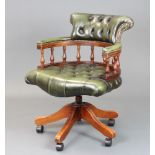 A Victorian style mahogany revolving office chair upholstered in green buttoned leather, raised on a