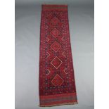A red ground Mashwani runner with 5 diamonds to the centre within a multi row border 243cm x 64cm
