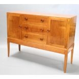 A 1950's Gordon Russell style walnut sideboard, fitted 3 drawers flanked by cupboards, raised on