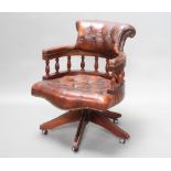 A tub back revolving office chair upholstered in brown buttoned leather