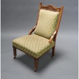 A Victorian carved walnut show frame nursing chair upholstered in green material raised on turned
