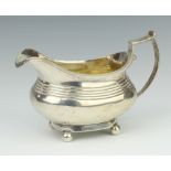 A George IV silver milk jug raised on ball feet with chased monogram, London 1825, 198 grams