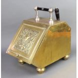 A Victorian embossed brass polished brass wedge shaped coal box raised on bun feet complete with