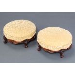 A pair of Victorian circular carved walnut show frame footstools, the seats upholstered in yellow