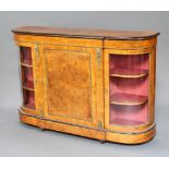 A Victorian figured walnut and ebonised D shaped credenza enclosed by a panelled door flanked by a