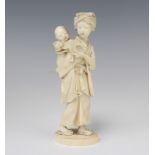 A Japanese Meiji period carved ivory Okimono of a robed lady holding a child on her back with a kite