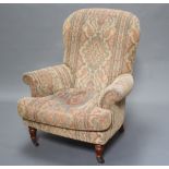 A Victorian style armchair upholstered in tapestry material, raised on turned supports