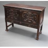 A 17th Century style carved oak dresser base enclosed by geometric panelled doors, raised on