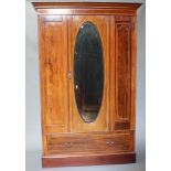 An Edwardian inlaid mahogany wardrobe with moulded cornice enclosed by an oval bevelled plate mirror