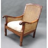 A hardwood double cane bergere armchair, raised on shaped supports