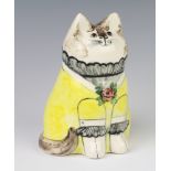A Rye Pottery seated cat by Bethel dated 1988, with glass eyes, wearing a yellow dress 19cm