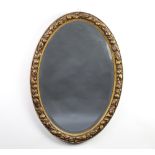 A 1930's oval bevelled plate wall mirror contained in a decorative gilt frame with fruit