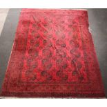 A red and black ground Afghan carpet with 28 octagons to the centre within a multi row border