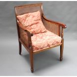 A mahogany framed library chair with cane work panels to the side and back raised on square