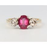 An 18ct yellow gold ruby and diamond ring, the centre oval stone approx. 1.5ct, flanked by 2
