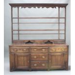 A Georgian oak dresser, the raised back with moulded and dentil cornice fitted 3 shelves above an