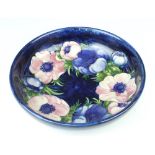 A William Moorcroft shallow bowl the blue ground decorated the anemone design, impressed signature