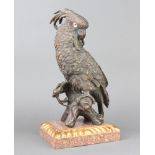 A bronze figure of a seated cockatoo with glass eyes, raised on a marble effect base 34cm h x 18cm w