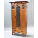 An Edwardian Art Nouveau light oak wardrobe with shaped cornice fitted a mirrored panelled door,