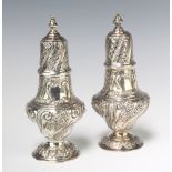 A matched pair of Edwardian repousse silver shakers with vacant cartouches, decorated with flowers