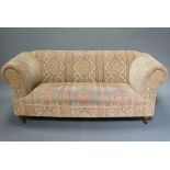 A Victorian style Chesterfield sofa upholstered in tapestry material raised on turned supports