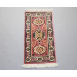 A pink and white ground Persian style machine made rug with geometric designs 122cm x 261cm
