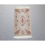 A beige floral patterned Chinese rug 130cm x 68cm