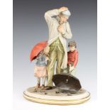 A Capodimonte figure group of an elderly gentleman with 2 children holding umbrellas 39cm