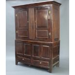 An 18th Century oak cabinet, the upper section with moulded cornice and enclosed by a panelled door,