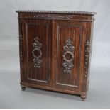 A 19th Century Indian carved "pine and coromandel" cabinet, fitted shelves enclosed by panelled