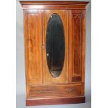 An Edwardian inlaid mahogany wardrobe with moulded cornice enclosed by an oval bevelled plate mirror