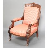 A Victorian carved walnut open armchair upholstered in striped pink material, raised on turned
