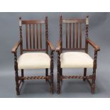 A pair of 1920's oak stick and rail back carver chairs with upholstered over stuffed seats, raised