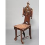 A Continental carved oak hall chair with pierced and carved back, solid seat, raised on outswept