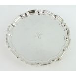 A silver card tray with Chippendale rim and engraved monogram, on scroll feet Sheffield 1965,