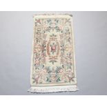 A white and floral patterned Chinese rug 129cm x 96cm Some staining