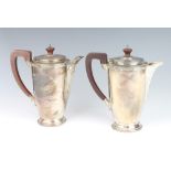A pair of silver coffee and milk jugs with Arts and Crafts decoration, fruit wood handles,
