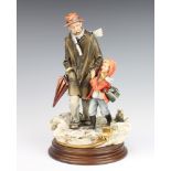 A Capodimonte group of an elderly man with child in a snowy landscape 28cm