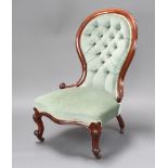 A Victorian mahogany spoon back nursing chair upholstered in blue buttoned material, raised on