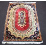 A machine made red, gold and blue ground Persian style carpet with oval central medallion Some light