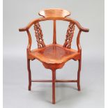 A Chinese carved and pierced hardwood corner chair raised on cabriole supports with X framed