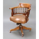 An Edwardian revolving mahogany stick and tub back office chair, raised on tripod supportsSome