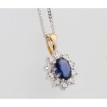 An 18ct yellow gold oval sapphire and diamond cluster pendant 18mm on a silver chain, centre stone