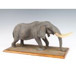 Tom Kenya, a composition figure of an elephant raised on a wood base 49cm The tail has been repaired