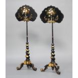 A pair of Victorian ebonised and gilt painted pole screens with shaped papier mache screens,