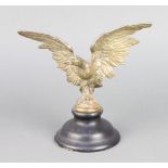 A gilt metal "car mascot" in the form of an eagle with wings outstretched, raised on an ebonised