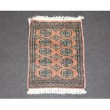 A pink ground Bokhara rug with 10 octagons to the centre 87cm x 64cm (some staining to the edge)